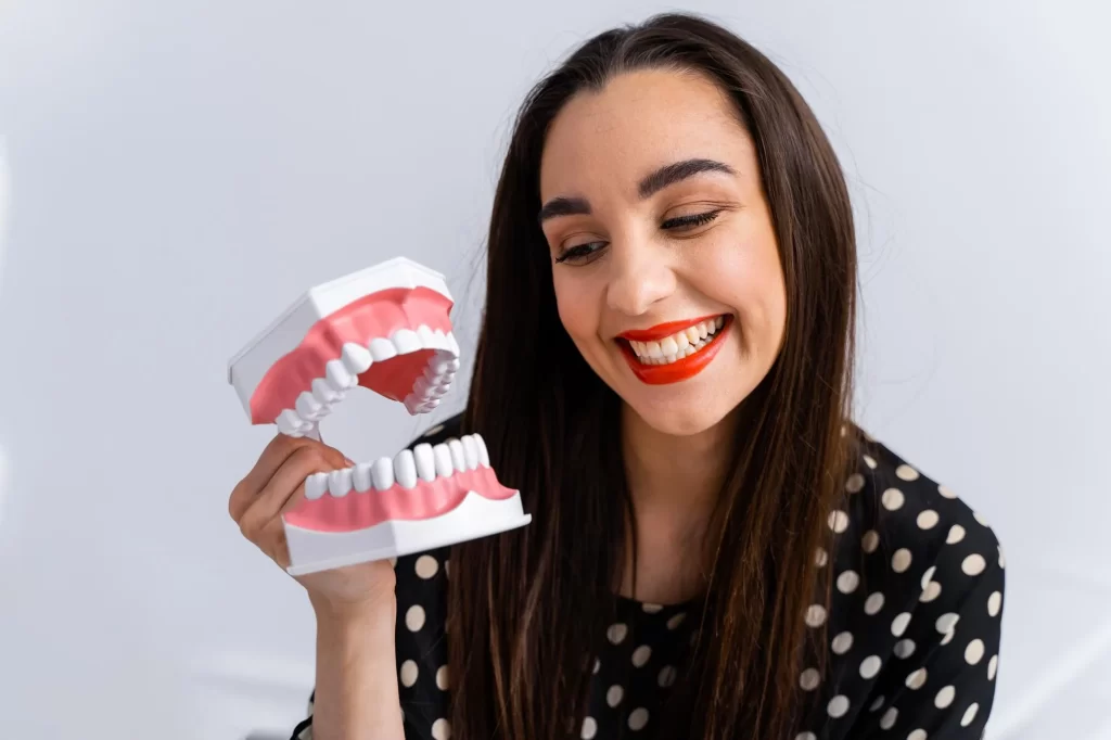 A woman holding a dental model before a Zirconium Veneer 